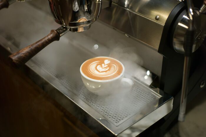 A steaming cup of latte art on an espresso machine, highlighting expensive items worth spending money.