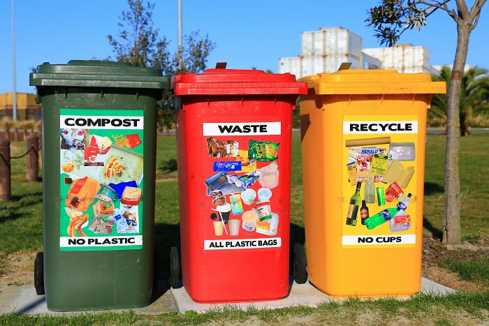 Recycling bins for compost, waste, and recycling in a park represent adulthood responsibilities for millennials.