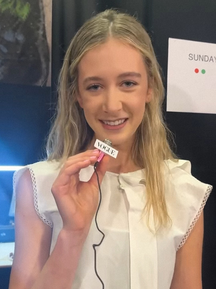 Young model holding Vogue badge, smiling after landing big modeling gig.