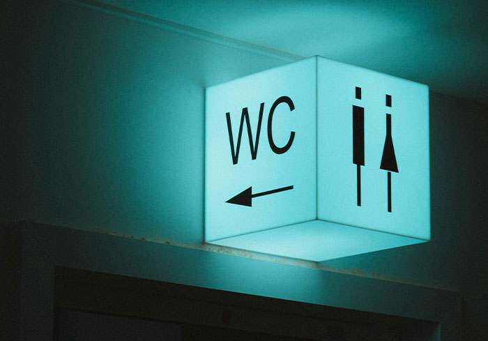 Illuminated restroom sign with WC and directional arrow, showcasing a common US symbol.