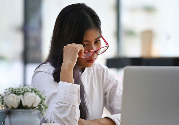 Woman with red glasses working on a laptop, representing normal US behavior unfathomable to Europeans.