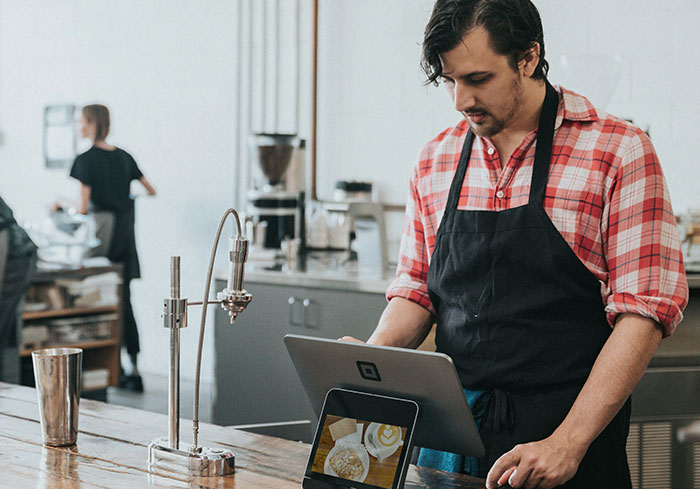 Barista in a café using a tablet register, showcasing a common aspect of US culture.