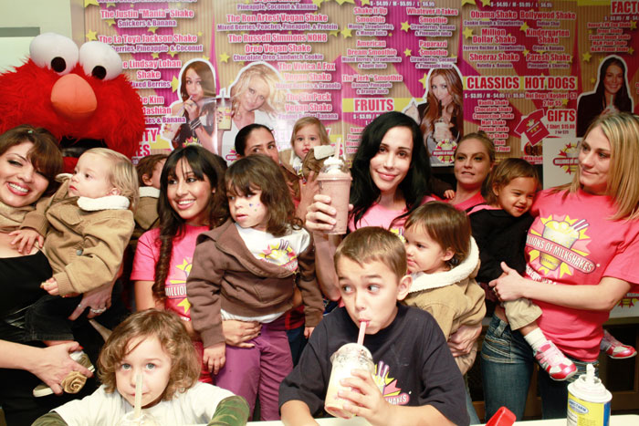 Nadya Suleman in a milkshake shop with her children and others, holding a milkshake and smiling.