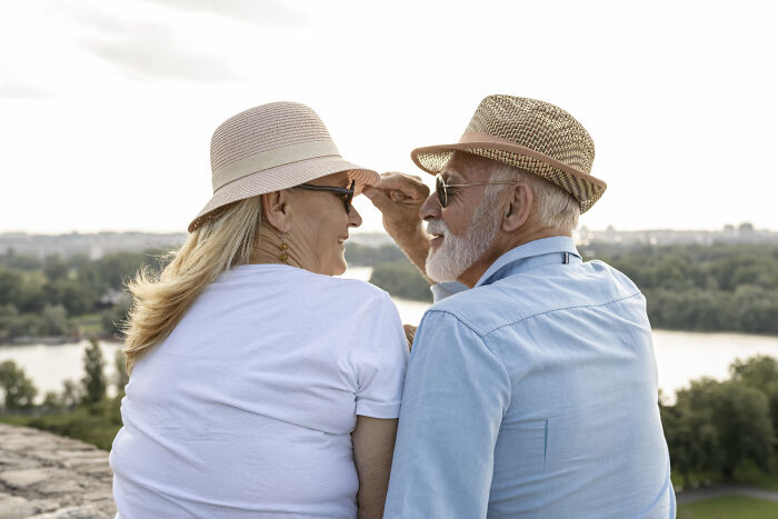 Elderly couple in hats enjoying a scenic view by the river, symbolizing middle class lifestyle.