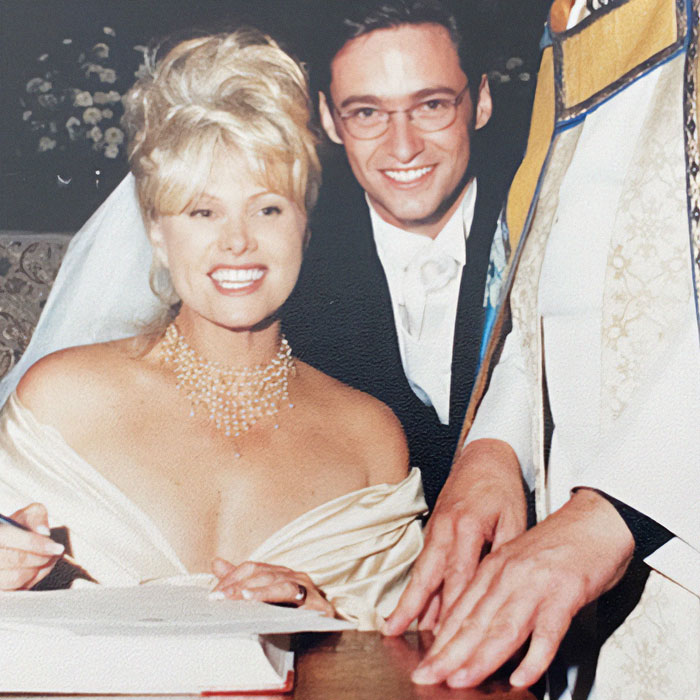 Deborra-Lee Furness and Hugh Jackman smiling at a wedding ceremony, signing documents together.