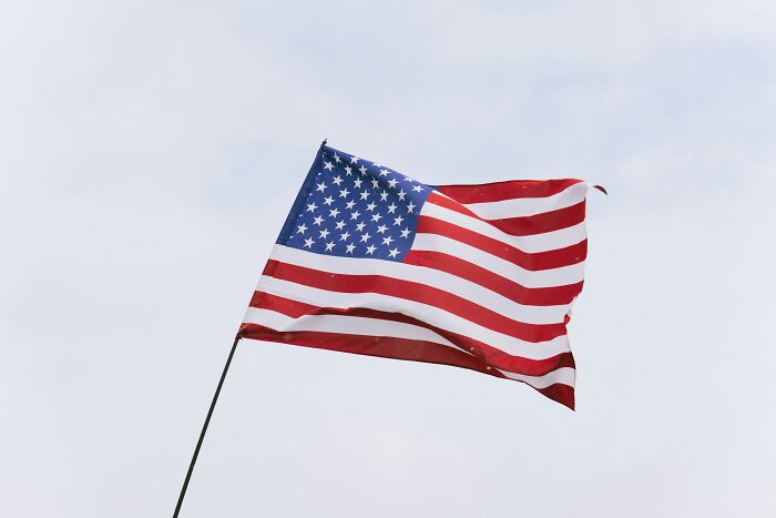 American flag waving against a clear sky, symbolizing themes related to the biggest scam in human history.