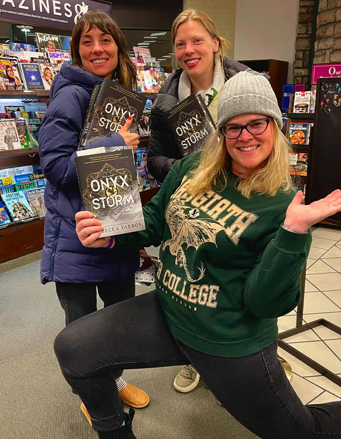 People excitedly holding copies of "Onyx Storm" in a bookstore.