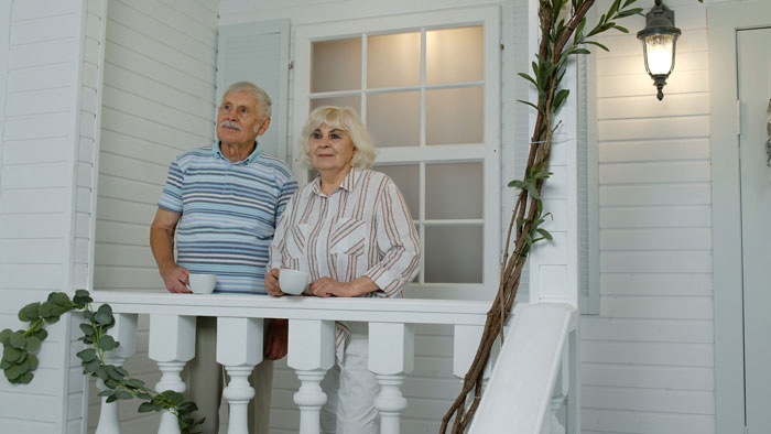 Elderly couple on porch, enjoying a peaceful moment, related to paying off parents' mortgage topic.