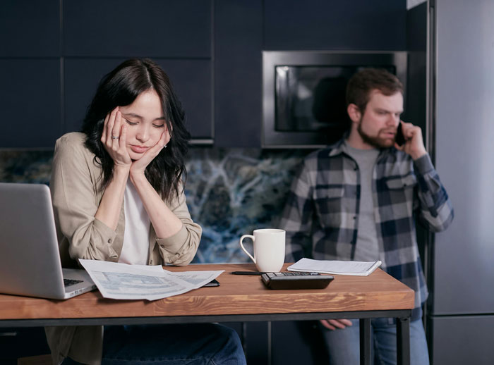 Man and woman in kitchen, dealing with mortgage documents and financial stress.