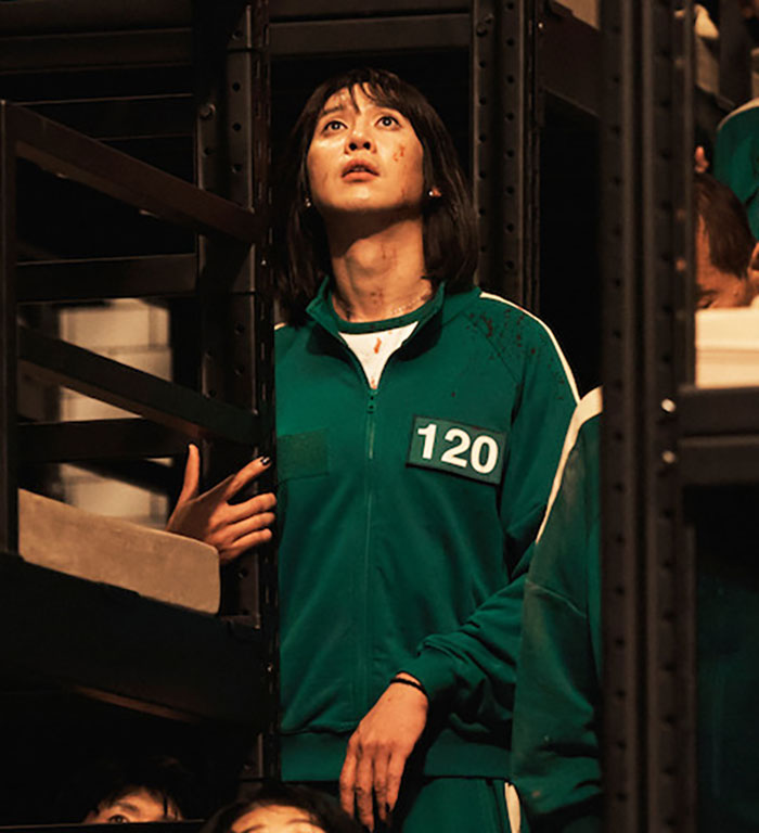 "Squid Game actor in a tense scene, wearing a green tracksuit with number 120.