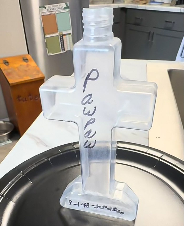 Cross-shaped bottle labeled "Pawpaw" on a kitchen counter, related to mom cleaning sons' dirt.