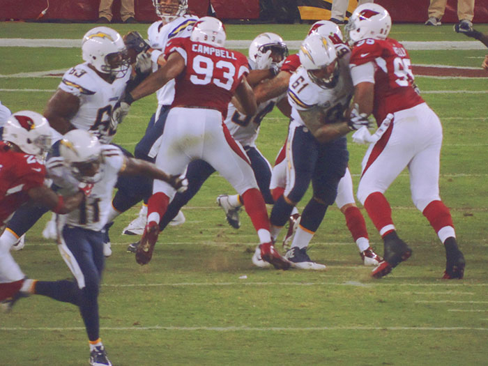 Football players from Chargers and Cardinals in action during a game, focusing on a defensive tackle.