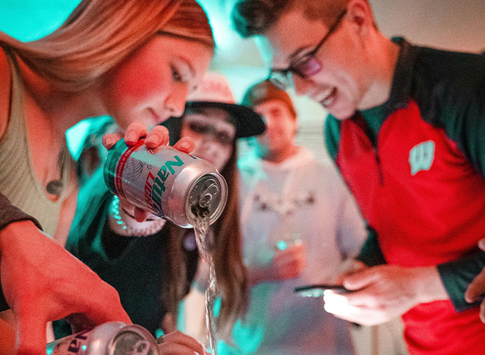 Young adults pouring drinks at a party, reminiscing high school peak moments.