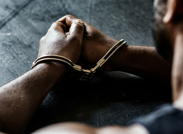 Hands in handcuffs resting on a dark surface, symbolizing consequences of cringey high school behaviors.