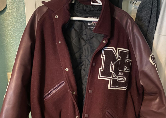 Vintage high school varsity jacket hanging in a closet.