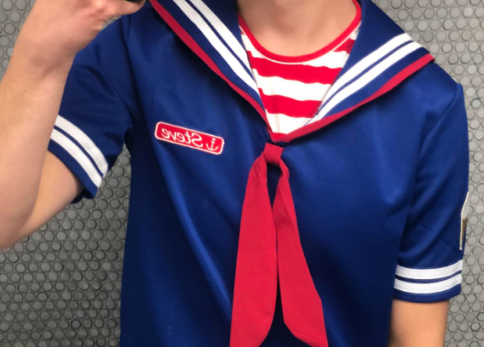 Person wearing a blue sailor costume with red details, possibly reminiscent of high school role-play.