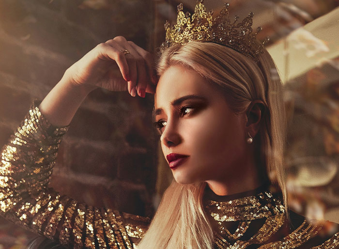 Blonde woman in a golden crown and sequined dress, embodying "I peaked in high school" attitude.