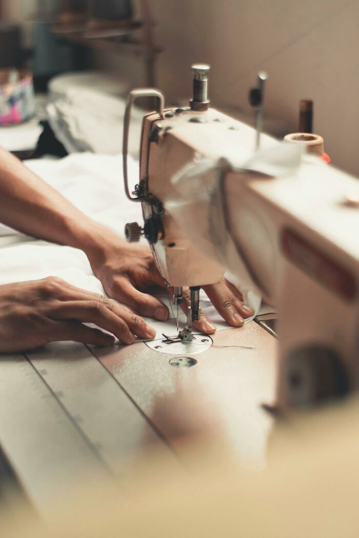 Hands using a sewing machine, showcasing a skill some people struggle to grasp despite simple explanations.