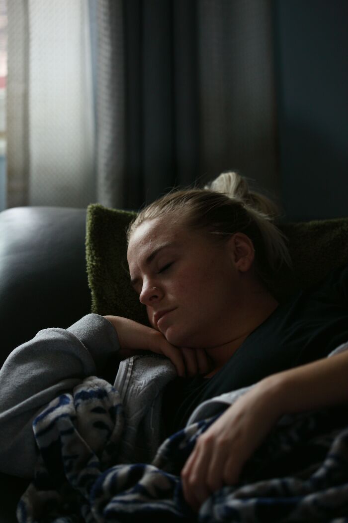 Person sleeping on a couch with a blanket, illustrating a moment of quiet relaxation.