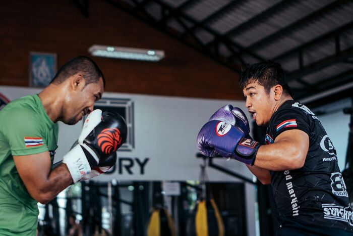 Two men boxing in a gym, focusing on weight-loss through exercise and fitness activities.