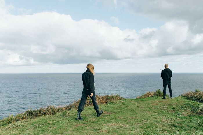 People walking on a grassy cliff by the sea, illustrating weight-loss tips like fun walks.