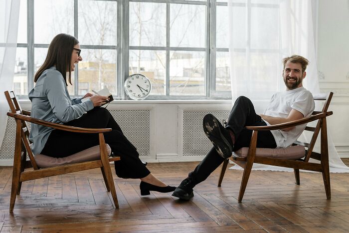 Two people sitting in chairs, smiling and engaged in conversation, conveying life-changing weight-loss tips.