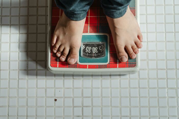 Feet on a red bathroom scale, representing weight-loss tips and progress toward shedding pounds.