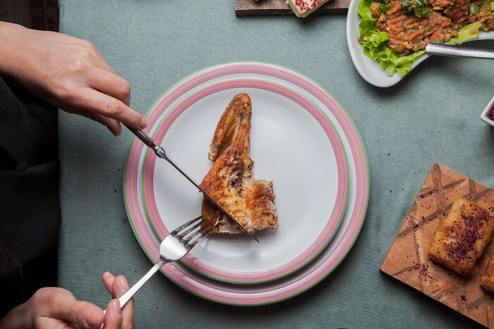 Person making food swaps with a chicken wing on a white plate, focusing on weight-loss strategies.