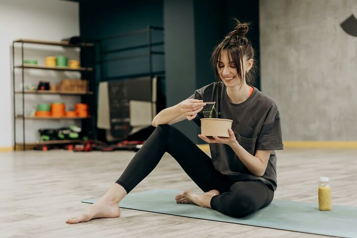 Woman enjoying a healthy meal on a yoga mat, illustrating weight-loss tips through lifestyle changes.