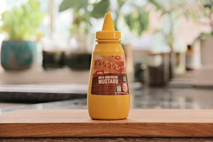 A bottle of mild American mustard, representing a lifetime supply win experience, on a kitchen counter.