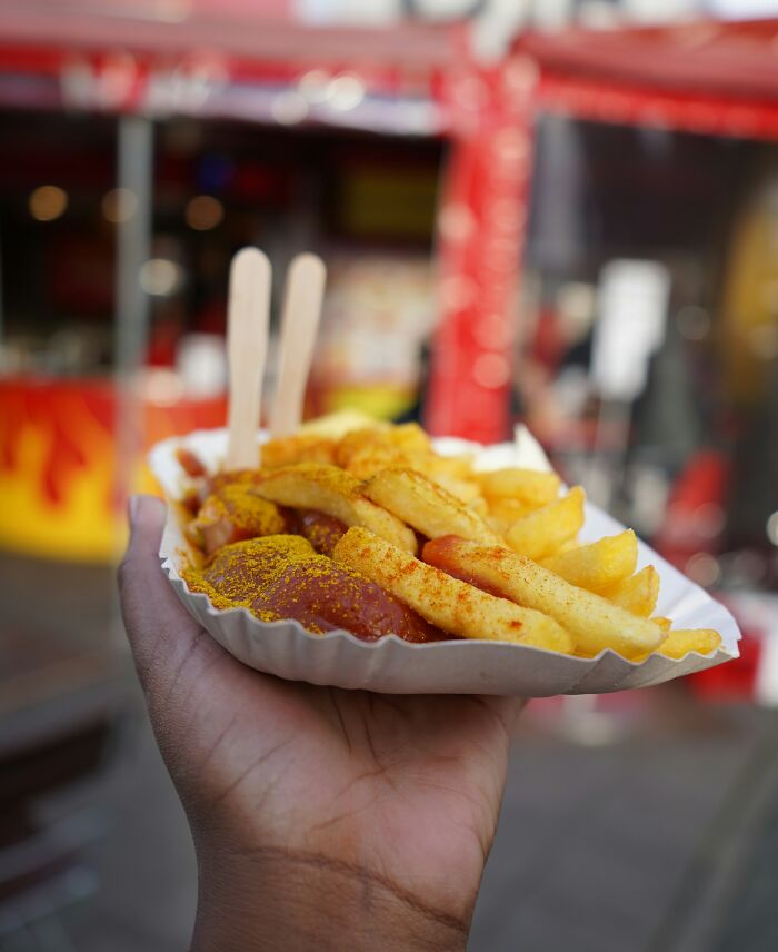 A hand holds a tray of seasoned fries and sausage, capturing a taste of a lifetime supply experience.