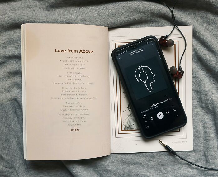 Open book on a gray sheet with a smartphone and earphones.