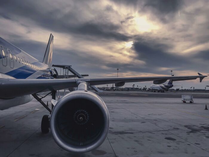 Airplane parked at the airport under a cloudy sky.