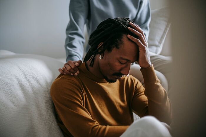 A man comforted by a hand on his shoulder, showing empathy as a non-sexual thing that turns women on.