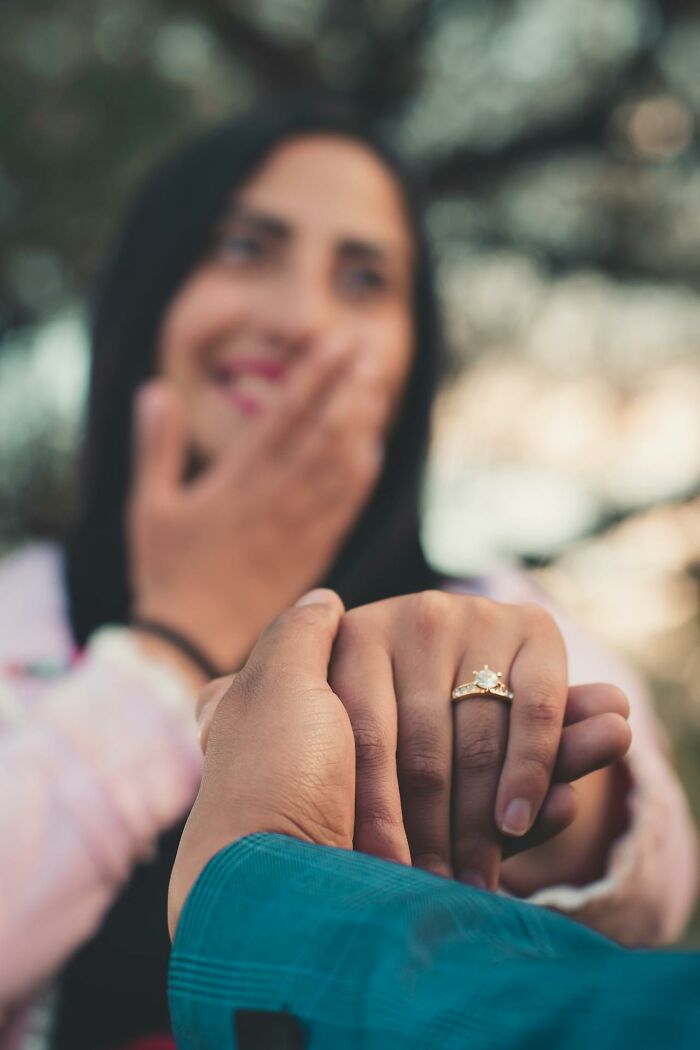 Person holding hands with an engagement ring, reflecting social norms in relationships.