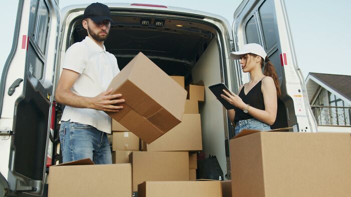 Two people unloading boxes from a van, potentially containing expensive items worth spending money on.