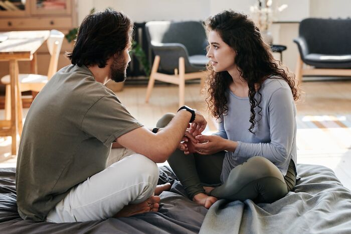 Man and woman sitting on a bed in conversation, focusing on connection and understanding, highlighting non-sexual attraction.