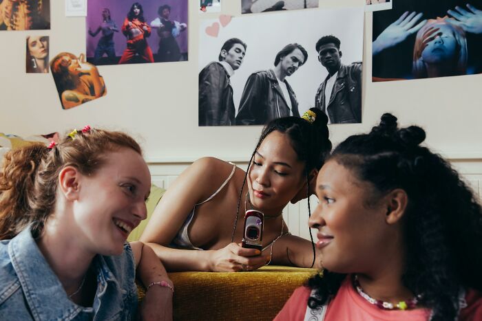 Teens smiling and talking in a room with posters, capturing friendship despite feeling like foreigners in a different country.