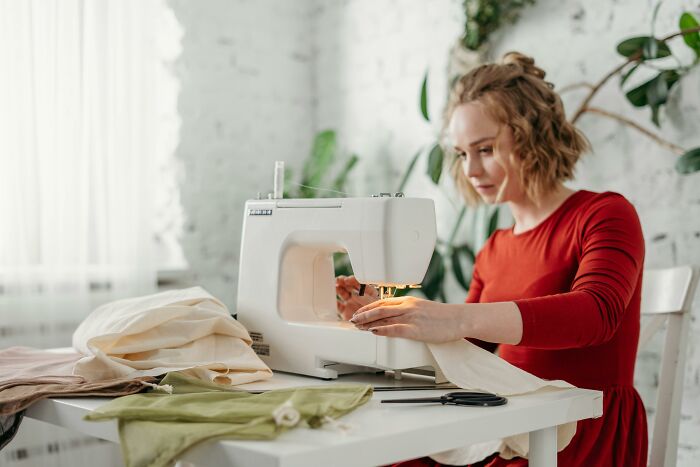 Woman sewing at home to save money and find more fulfillment in 2025.