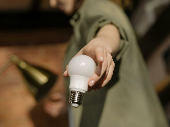 Person holding a light bulb, showcasing a home hack for an affordable and stylish living space.