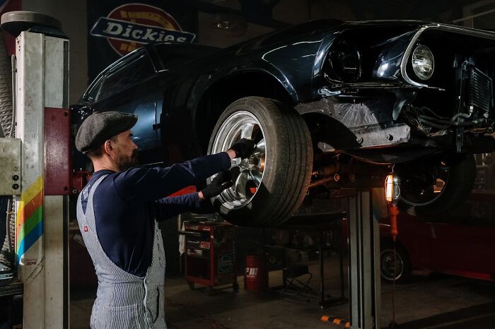 Mechanic working on a car in a garage, showcasing non-sexual skills that can be attractive to women.