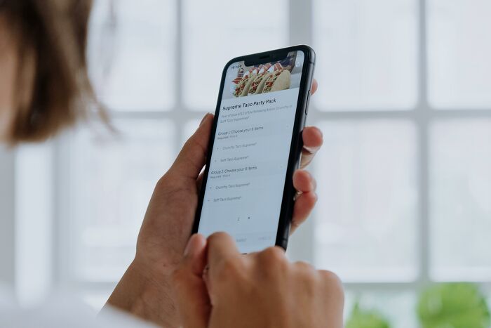 Person viewing a food menu on a smartphone, considering an unethical life hack for ordering food.