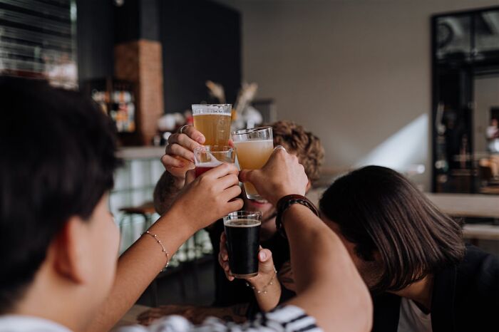 People clinking glasses in a bar celebrating, highlighting social norms.