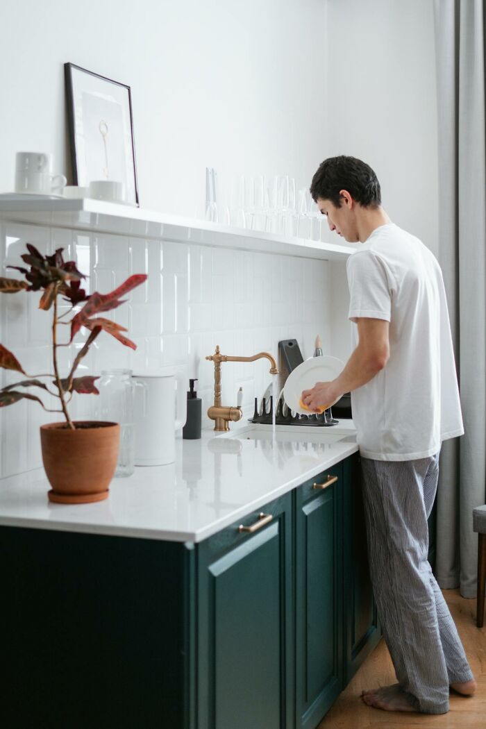 Man doing dishes in a modern kitchen, a non-sexual action that turns women on.