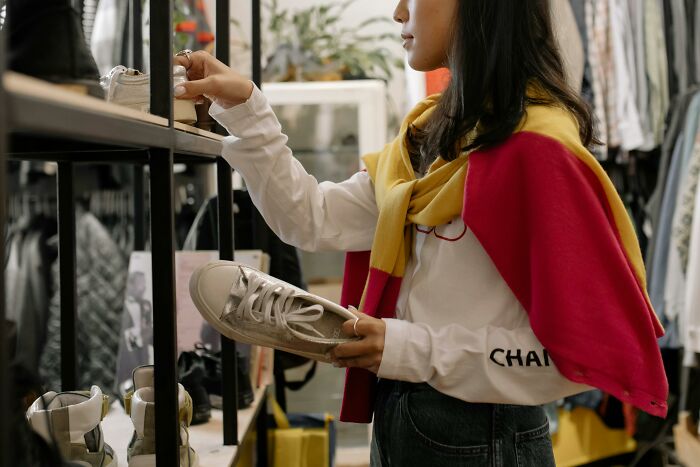 Person in a shop, examining shoes on a shelf.