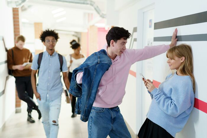 Young millennials interacting and using smartphones in a modern hallway.