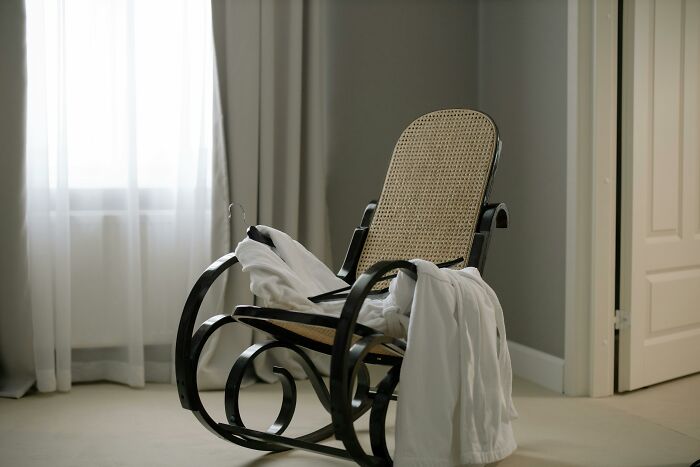 Empty rocking chair in a dimly lit room with a white sheet draped over it.