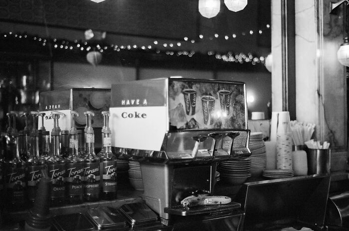 Vintage soda fountain setup with Coke dispenser and syrup bottles, evoking a simpler time.