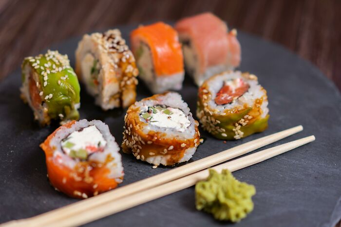 Gourmet sushi rolls on a slate plate with chopsticks and wasabi, showcasing expensive items worth spending money on.