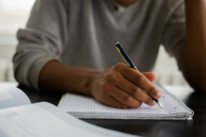 Person writing in a notebook, symbolizing displays of genius and creativity.